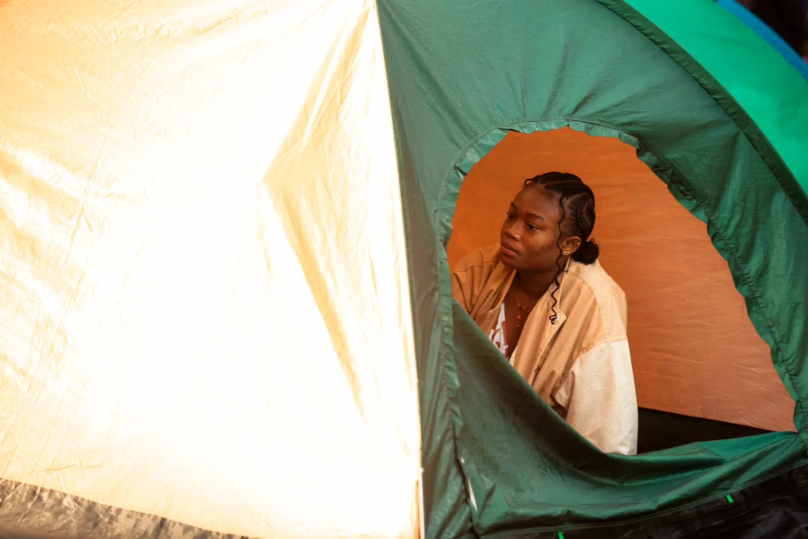A woman sitting in the doorway of a green tent