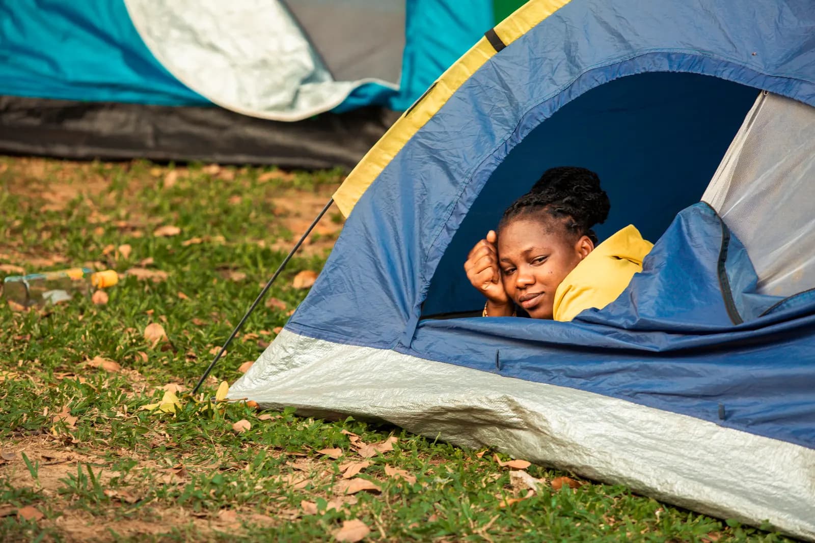 A woman resting in the doorway of a blue tent
